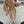 Vrouw in elegante beige wollen jas met dubbele rij knopen, witte handtas en hakken. Modieuze herfstoutfit, stedelijke achtergrond.