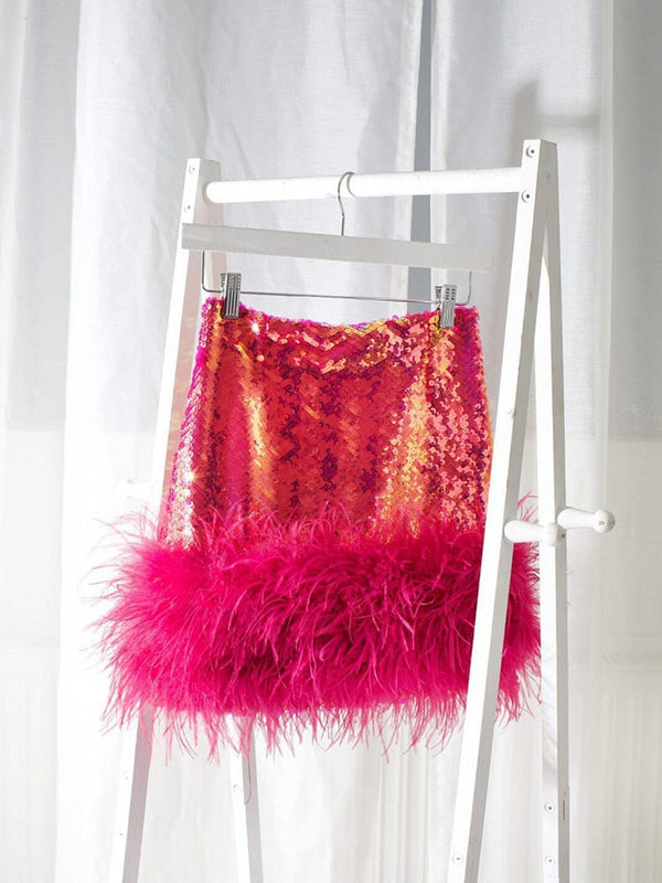 Roze paillettenrok met verenrand, glanzend en opvallend, op witte kledinghanger. Perfect voor feestelijke outfits en modieuze evenementen.