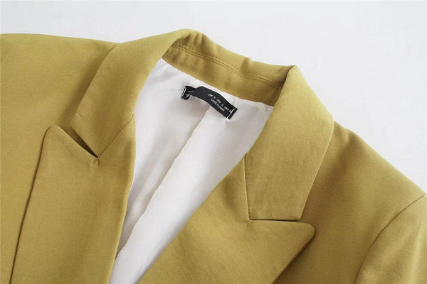 Gele blazer met witte voering en zwarte label, close-up. Stijlvolle damesmode, formele kleding, trendy jasje voor zakelijke en casual gelegenheden.