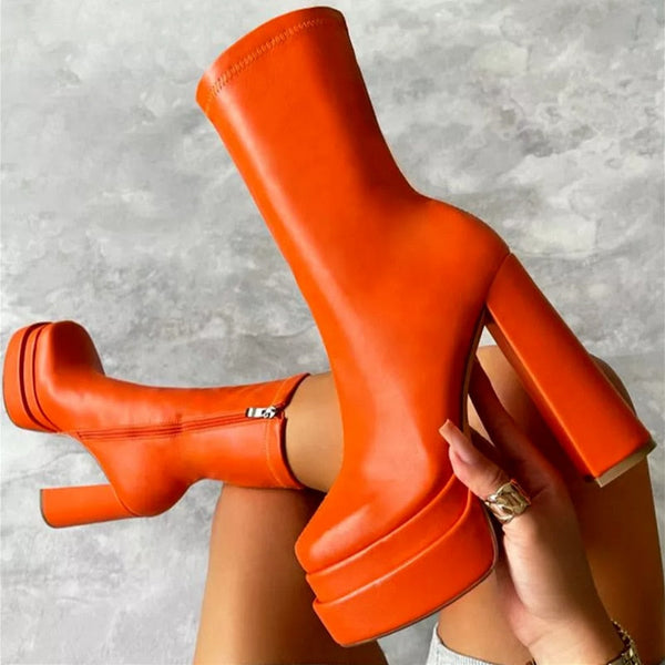 Oranje platformlaarzen met hoge hakken, trendy design, gedragen door een persoon. Perfect voor modieuze herfst- en winteroutfits.