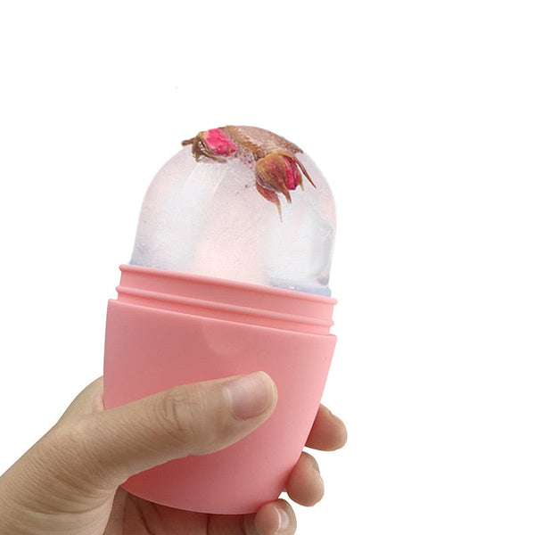 Hand houdt roze siliconen ijsroller met ingesloten rozenknoppen, ideaal voor huidverzorging en gezichtsverfrissing. Perfect voor beauty routine.