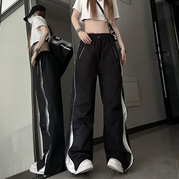 Vrouw in zwarte wijde broek met witte strepen, crop top en pet, poseert voor spiegel. Trendy streetwear mode, casual outfit, urban stijl.
