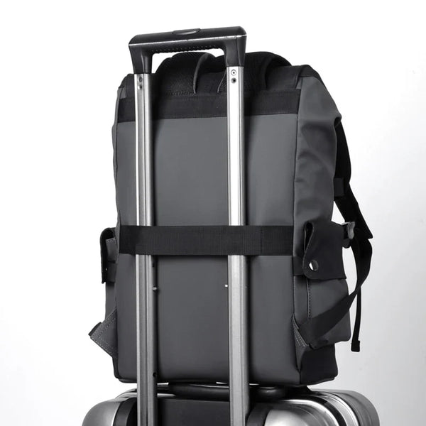 Grijze rugzak bevestigd aan een zilveren koffer met uitschuifbare handgreep, ideaal voor reizen. Rugzak en koffer combinatie, reisaccessoires.
