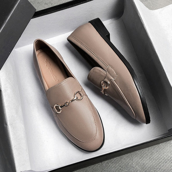 Beige leren loafers met metalen kettingdetail in een open schoenendoos, stijlvolle damesschoenen, casual en elegant design.