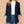 Vrouw in donkerblauwe blazer met opgerolde mouwen, witte top en blauwe jeans. Stijlvolle damesmode, casual chic outfit voor kantoor of dagelijks gebruik.