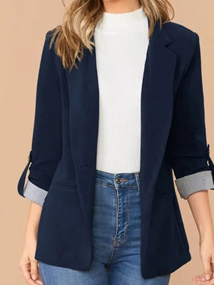 Vrouw in donkerblauwe blazer met opgerolde mouwen, witte top en blauwe jeans. Stijlvolle damesmode, casual chic outfit voor kantoor of dagelijks gebruik.