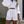 Vrouw in witte zomerset met pofmouwen en korte broek, draagt een strooien tas. Trendy damesmode, casual zomeroutfit, stijlvolle kleding.