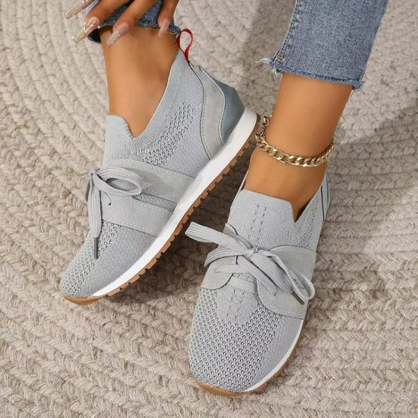 Grijze dames sneakers met veters, gebreid bovenwerk en witte zool, gedragen met jeans. Comfortabele en modieuze schoenen voor dagelijks gebruik.