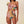 Vrouw in roze asymmetrische bikini met kleurrijke patronen en ruches, modieuze strandkleding, zomertrends, hoge taille, sieradenaccessoires.