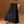 Zwarte geplooide rok met riem, hangend op houten hanger, naast retro rieten stoel. Modieuze dameskleding, elegant design, herfstcollectie.