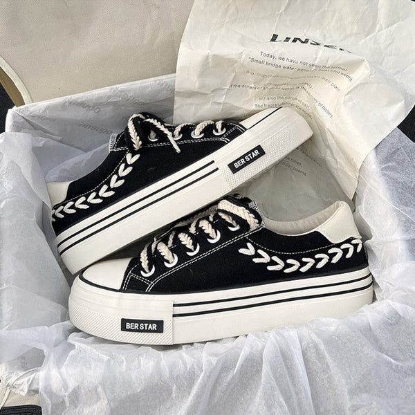 Zwarte canvas sneakers met witte veters en decoratieve stiksels in een schoenendoos. Trendy platformzolen, casual stijl, unisex ontwerp.