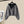Grijze cropped hoodie met knopen en capuchon, hangend aan een hanger. Modieuze dameskleding, casual streetwear, comfortabele pasvorm.