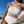 Vrouw in witte badpak met kleurrijke zigzagpatronen, zittend op een terras met uitzicht op zee. Zomer, strandmode, trendy badkleding.