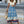 Vrouw in bohemian maxi rok met blauw-wit patroon en knoopblouse, draagt rieten tas. Zomerse mode, straatstijl, casual chique outfit.