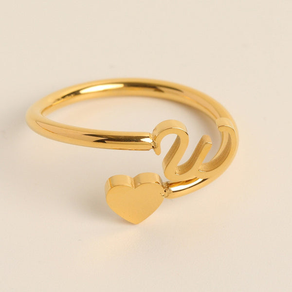 Gouden ring met hartvormig detail en sierlijke initialen, minimalistisch ontwerp, perfect als cadeau, elegante damesring, modieuze sieraden.