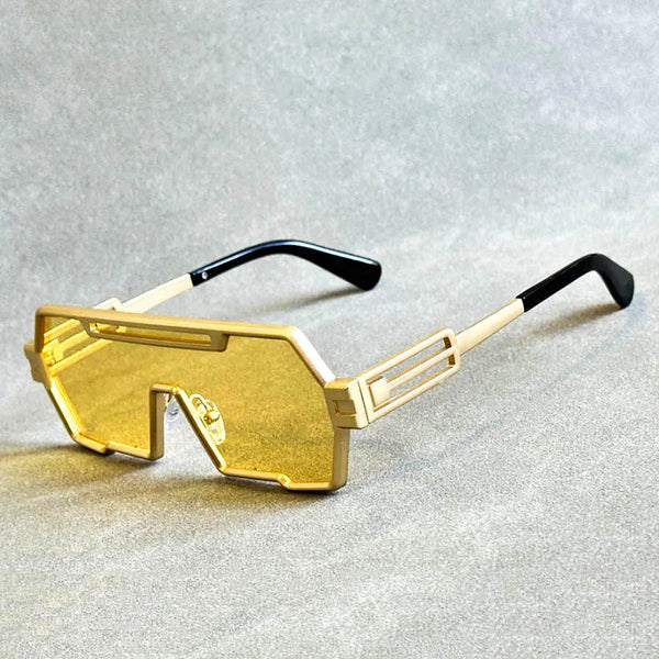 Gouden futuristische zonnebril met gele lenzen en zwart-witte poten op grijze achtergrond. Trendy unisex accessoire, modieuze zonnebril.