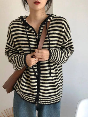 Vrouw draagt zwart-wit gestreepte hoodie met capuchon, casual mode, herfstkleding, bruine schoudertas, trendy damesoutfit.