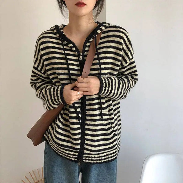 Vrouw draagt zwart-wit gestreepte hoodie met capuchon, casual mode, herfstkleding, bruine schoudertas, trendy damesoutfit.