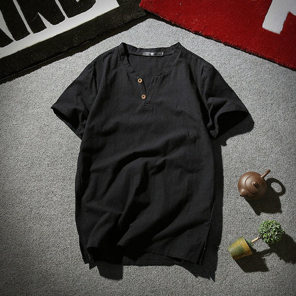 Zwarte katoenen heren T-shirt met korte mouwen en houten knopen, casual stijl, op grijze vloer met theepot en plant, modieuze herenkleding.