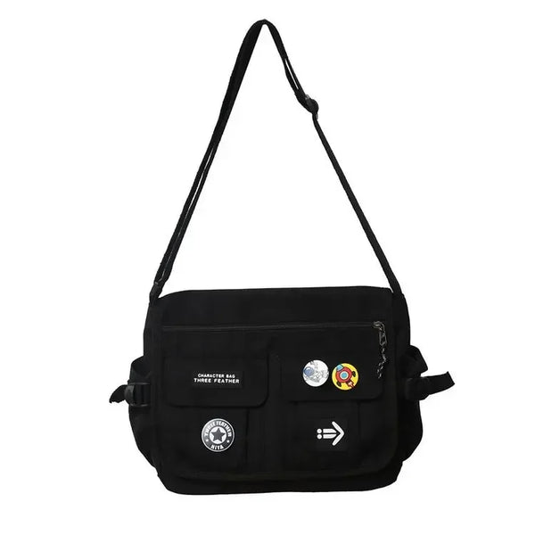 Zwarte schoudertas met verstelbare riem, meerdere vakken en decoratieve pins. Ideaal voor dagelijks gebruik en modieuze accessoires.