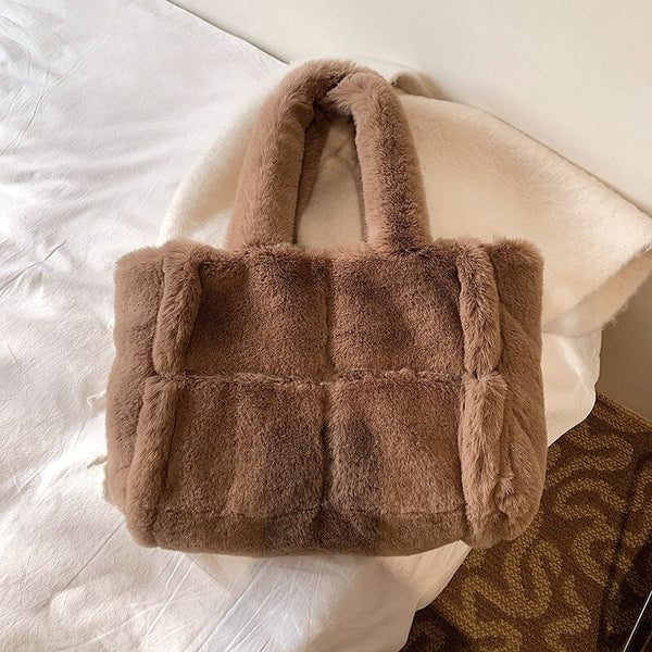 Pluche bruine handtas op bed, modieuze damesaccessoire, zachte faux fur tas, trendy wintermode, stijlvolle schoudertas voor dagelijks gebruik.