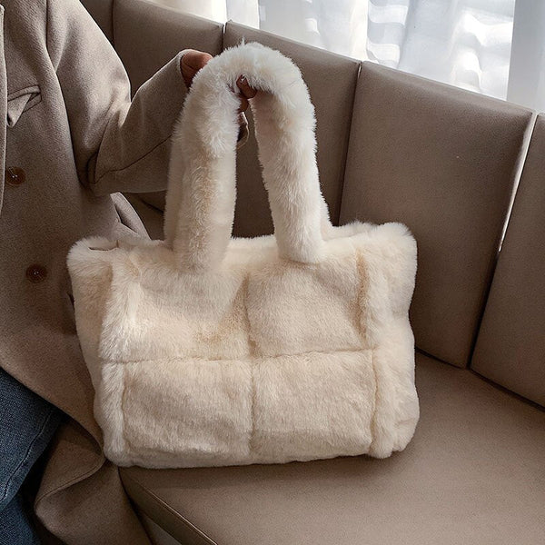 Witte pluchen handtas op beige bank, modieuze winteraccessoire, zachte faux fur tas met handvatten, trendy damesmode, stijlvolle tas voor dagelijks gebruik.