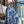 Vrouw in witte crop top en blauwe tropische maxi-rok op balkon met stad en bergen op achtergrond. Zomermode, stedelijk uitzicht, trendy outfit.