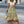Vrouw in bohemian maxi-rok met etnisch patroon, witte knoopblouse en rieten tas. Zomerse mode op straat, trendy boho-chic stijl.