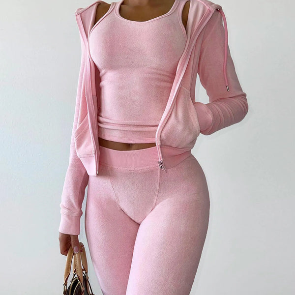 Vrouw in roze sportkleding, bestaande uit een tanktop, legging en hoodie, houdt een tas vast. Perfect voor fitness, yoga en casual mode.
