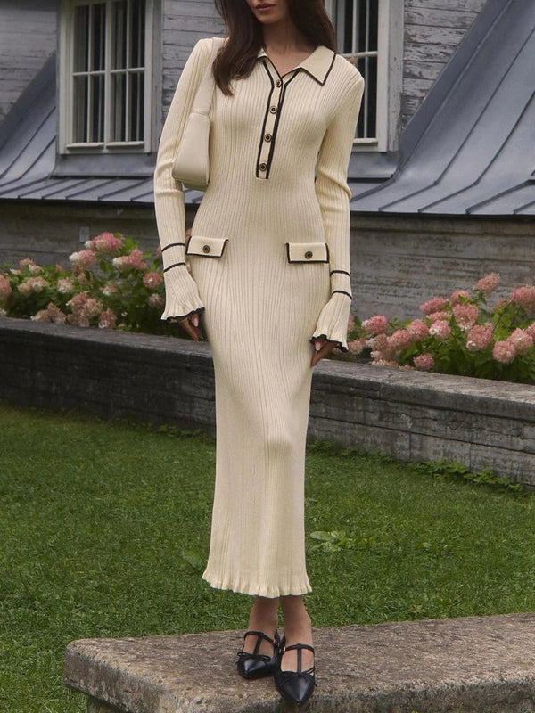Vrouw in elegante crèmekleurige gebreide jurk met zwarte knopen en details, staand in tuin. Modieuze herfstkleding, stijlvolle damesmode.