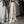 Vrouw in trendy beige wijde broek met ritsen, zwarte crop top en gele sneakers poseert voor spiegel. Streetwear mode, casual outfit.