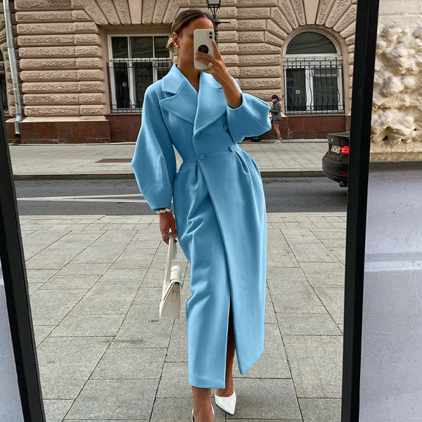 Vrouw in lange blauwe jas, straatmode, herfstkleding, elegante stijl, stedelijke achtergrond, witte tas en schoenen, modetrend 2023.