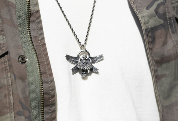Herenketting met zilveren adelaarshanger, gedragen op wit T-shirt en camouflagejas. Stijlvolle mannenaccessoire, modieuze sieraden.