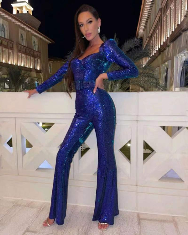 Vrouw in blauwe glitter jumpsuit poseert op balkon bij nacht, omringd door architectuur. Modieuze avondkleding, glamour, nachtelijke uitstraling.