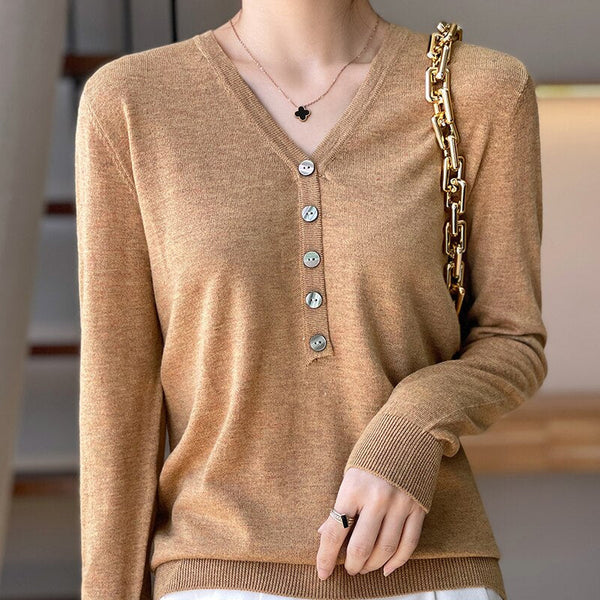 Vrouw draagt beige trui met V-hals en knopen, gouden kettingtas over schouder. Modieuze dameskleding, herfststijl, casual elegantie.