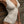 Vrouw in gestreept beige-wit badpak leunt tegen houten muur. Elegante strandmode, zomerse stijl, trendy badkleding, luxe horloge.
