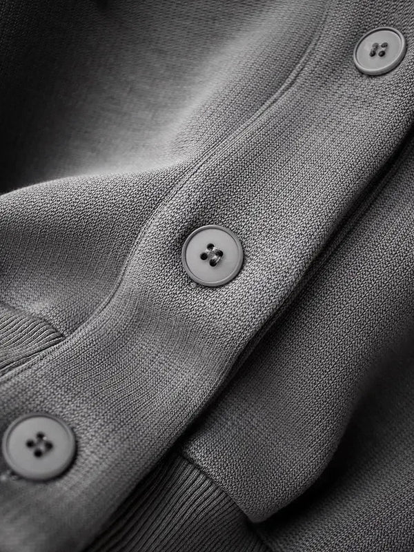 Grijze gebreide trui met knopen, close-up. Hoogwaardige stoftextuur, modieuze herenkleding, comfortabele en stijlvolle wintermode.