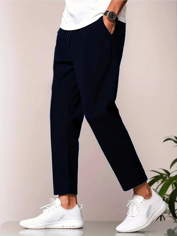 Man in donkerblauwe broek en witte sneakers, zijaanzicht. Stijlvolle casual mode, comfortabele herenkleding, moderne schoenen.