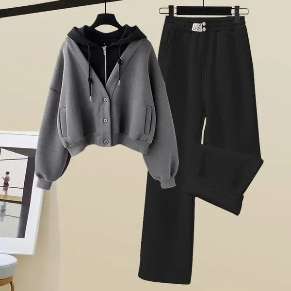 Grijze hoodie en zwarte broek set, casual dameskleding, comfortabele herfst- en winteroutfit, modieuze streetwear, hangend aan kledinghangers.
