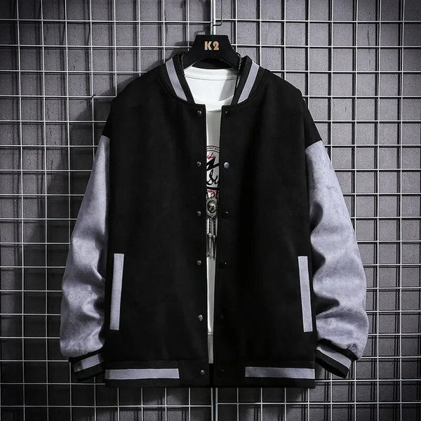 Zwart-grijze varsity jas op hanger, moderne streetwear stijl, met geribbelde boorden en knoopsluiting, tegen een metalen raster achtergrond.