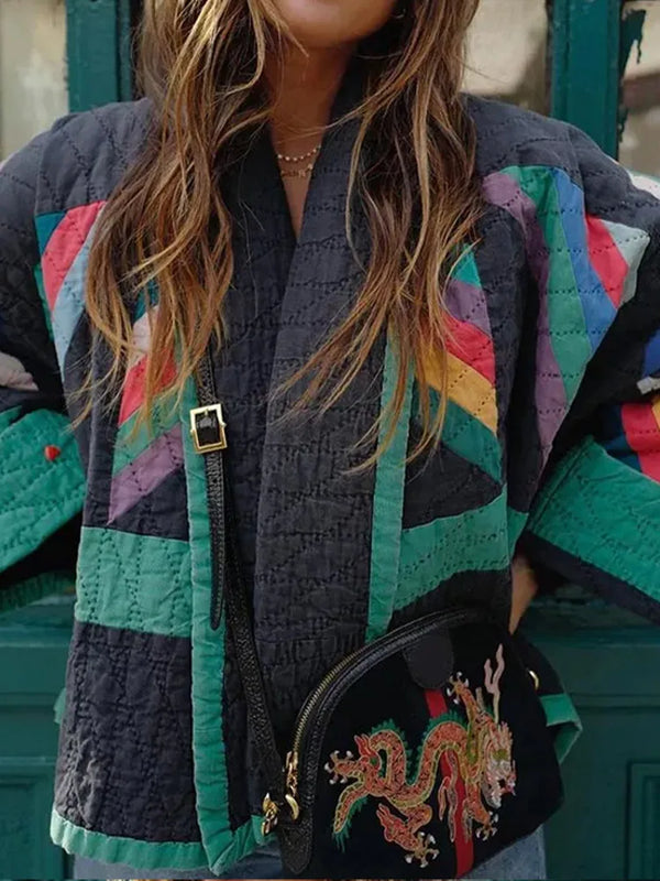Vrouw draagt kleurrijke patchwork jas met geometrisch patroon en een zwarte tas met drakenborduursel. Modieuze streetwear outfit.