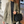 Vrouw in stijlvolle beige blazer met zwarte trui en gewatteerde zwarte handtas, wandelend op straat. Mode, herfstkleding, damesmode.