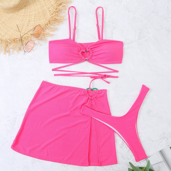 Felroze bikini set met hartvormige details, bestaande uit een bandeau top, strikslip en rok. Perfect voor strandmode en zomerse stijl.