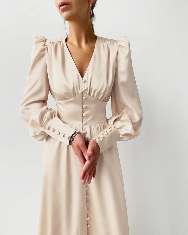 Elegante vrouw in crèmekleurige jurk met lange mouwen en knoopdetails, minimalistische mode, stijlvolle dameskleding, moderne outfit.