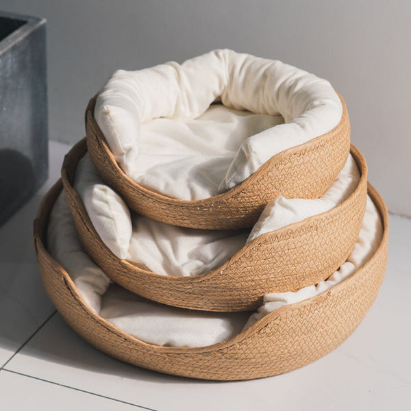 Drie gestapelde, ronde kattenmanden van gevlochten riet met zachte, witte kussens, ideaal voor huisdierencomfort en interieurdecoratie.