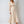 Elegante beige midi-jurk met lange pofmouwen en knoopsluiting, gedragen door een model. Perfect voor modieuze dameskleding en avondkleding.