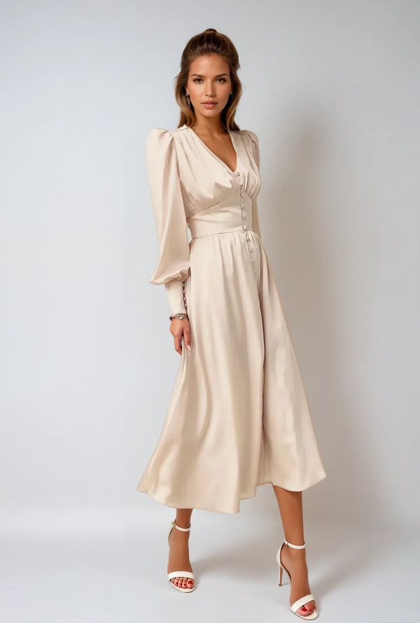 Elegante beige midi-jurk met lange pofmouwen en knoopsluiting, gedragen door een model. Perfect voor modieuze dameskleding en avondkleding.