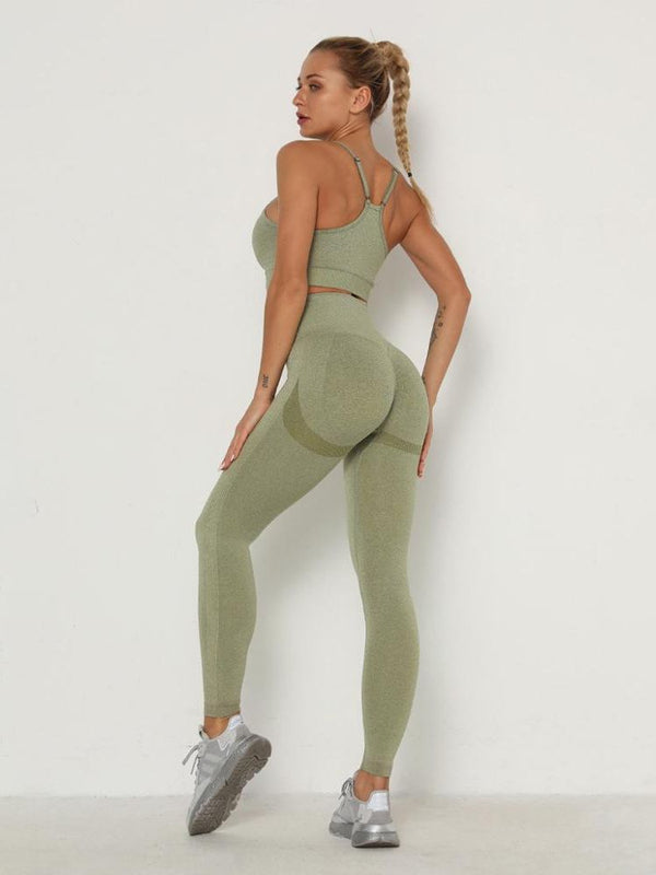 Vrouw in groene sportlegging en sportbeha, poseert tegen witte achtergrond. Fitnesskleding, sportoutfit, actieve levensstijl.