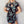 Vrouw in zwarte cheongsam-jurk met turquoise drakenprint, korte mouwen en sleutelgat halslijn, tegen een neutrale achtergrond.