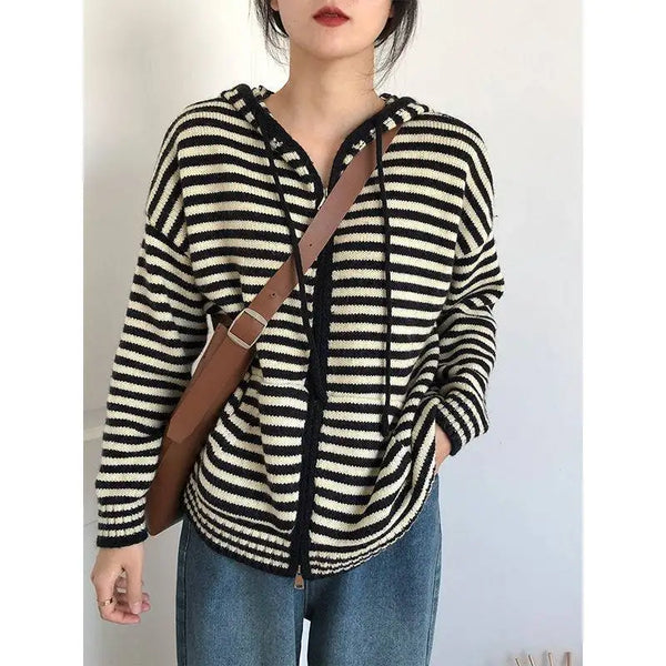 Vrouw draagt zwart-wit gestreepte trui met capuchon en bruine schoudertas, casual mode, herfstkleding, trendy damesoutfit, comfortabele stijl.